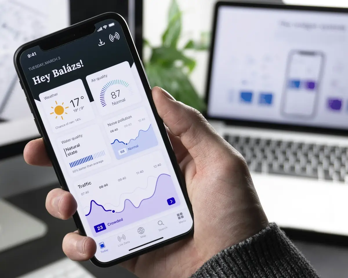 Hand holding a smartphone displaying a modern mobile app dashboard